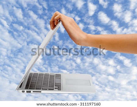 Woman's hand open laptop with beautiful cloud and sky background
