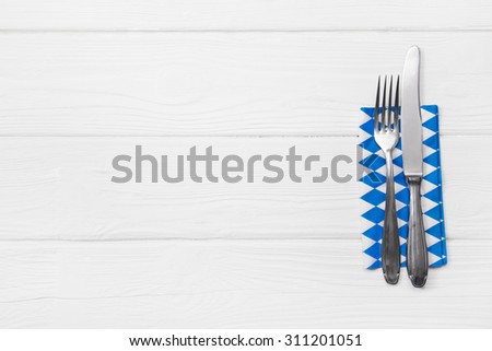 Wooden white background for a menu card with cutlery in blue white checked colors for restaurants and gastronomy placards.