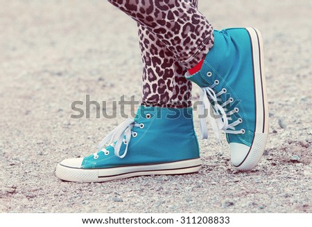 Woman's legs in blue sneakers in Finland. She is wearing a leopard-print pants. Image includes a effect.