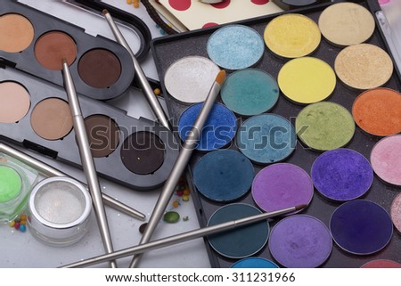 Colorful set of professional palette of eyeshadow red orange green violet pink yellow purple black beige brown colors foundation powder and make-up brushes on white background, horizontal picture