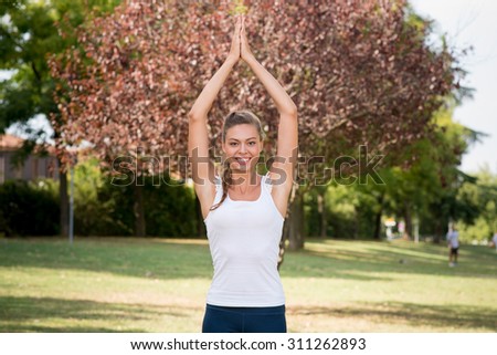 Young beautiful smiling woman practices yoga in a park