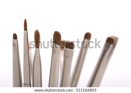 Set of different professional natural soft make-up small brushes for eyeshadow for visagistes grey and brown colors on white background, horizontal picture