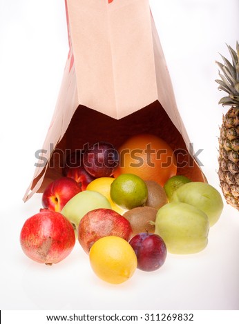 Fresh tropical fruits of pineapple orange juicy grapefruit yellow lemon ripe nectarine purple plum red pomegranate kiwi lime and green apple and paper pack on white background, vertical picture