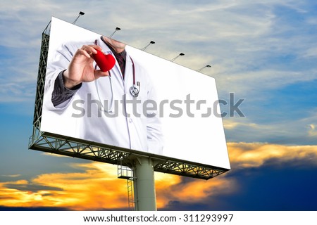 doctor holding red heart shape on billboard with white space
