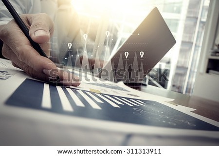 business documents on office table with smart phone and digital tablet and graph financial with social network diagram and man working in the background Royalty-Free Stock Photo #311313911