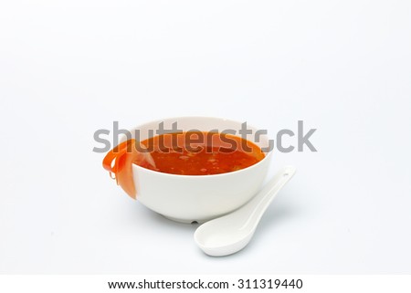 Red tomato cream soup in white ceramic cup isolated on white background.
