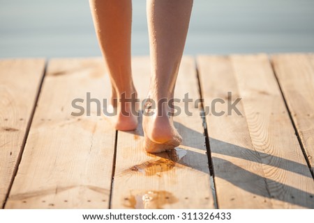 Wet human footprints on bright wooden plank floor. Walk from beach to hotel or home. Abstract backgrounds and wallpapers. Holidays and vacations in summer.