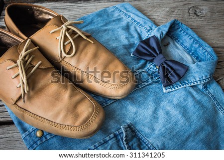 Men's casual outfits with jeans shirt, bow tie and brown shoes on wooden background