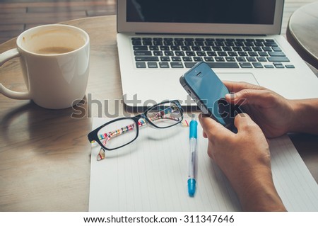 Vintage tone image for woman hold mobile phone on working time with coffee