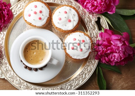 Composition with cup of coffee, muffins and peony flowers on tray, on wooden background