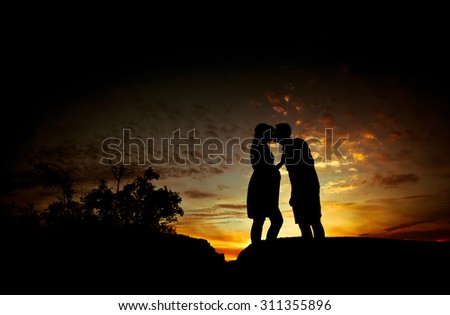 Pregnant couple silhouettes at sunset