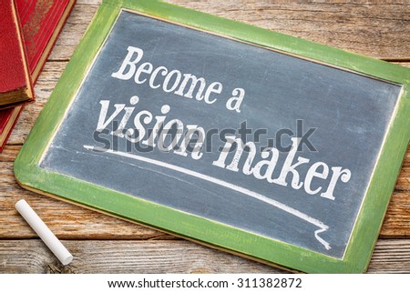 Become a vision maker - motivational advice on a slate blackboard with a white chalk and a stack of books against rustic wooden table