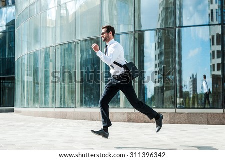 Hurrying to work. Full length of young businessman looking forward while running along the street Royalty-Free Stock Photo #311396342