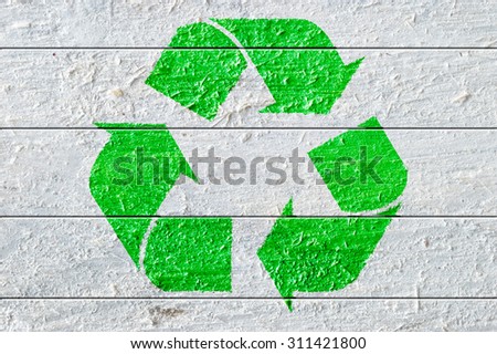 Green recycle symbol painted on a white natural textured wood. Copy space for editor's text.
