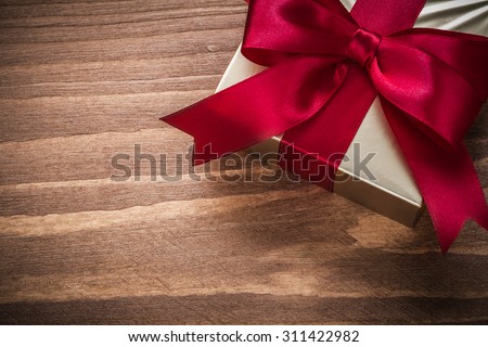 Packed glittery gold present container on vintage wooden board. Royalty-Free Stock Photo #311422982