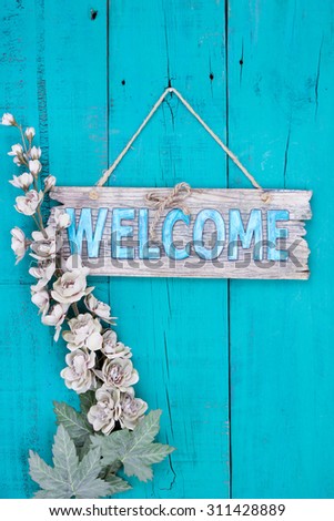 Rustic welcome sign with flowers hanging on antique teal blue wooden background