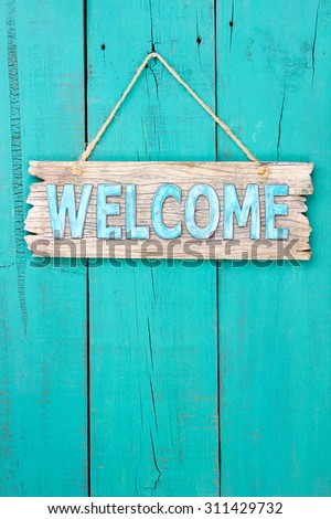 Rustic welcome sign hanging on antique teal blue wooden background