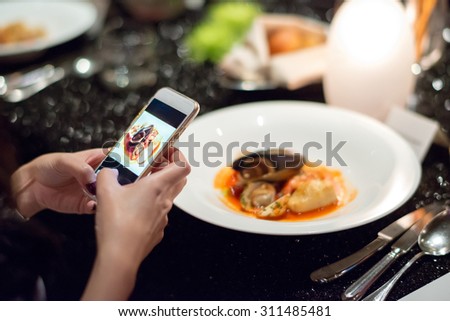 girl Using Smart phone taking her italian seafood dish