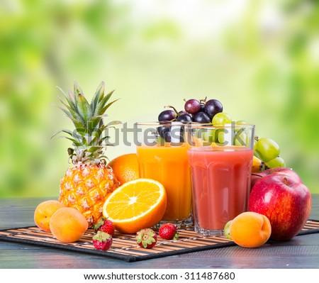 Fresh juice with fruits on wooden table with nature green background