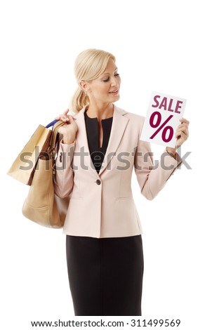 Portrait of smiling middle age woman standing against white background. Middle age female holding hand many shopping bags and sale sign.