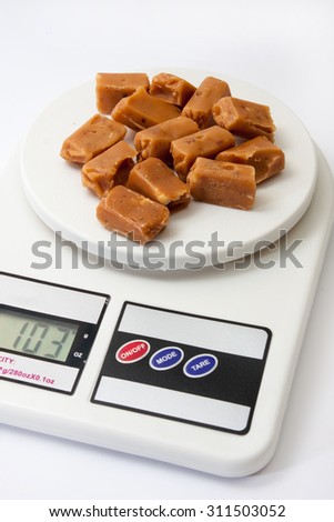 Caramel candies on white digital kitchen scale.