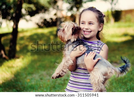 girl in a striped sweater smiles and holds a small dog
