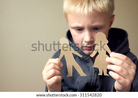 Confused child with cutting paper parents, family problems, divorce, custody battle, suffer concept 