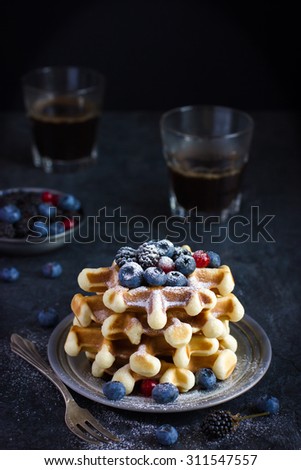 waffles with fresh berries and powdered sugar on dark background