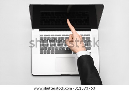 Business and technology topic: the hand of man in a black suit showing gesture against a gray and white background laptop in the studio isolated top view