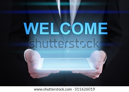 Businessman holding a tablet pc with "Welcome" text on virtual screen. Internet concept. Business concept.