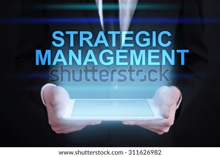Businessman holding a tablet pc with "Strategic management" text on virtual screen. Internet concept. Business concept.