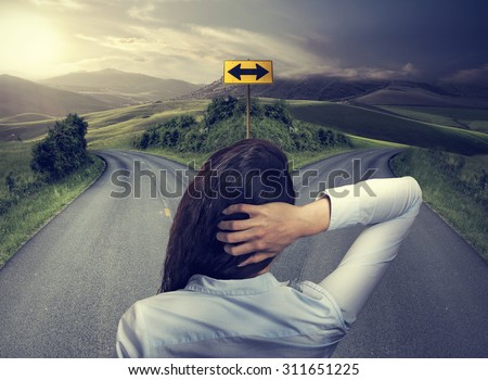 business woman in front of two roads thinking deciding hoping for best taking chance Royalty-Free Stock Photo #311651225