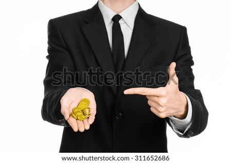Money and business theme: a man in a black suit holding a pile of gold coins in the studio on a white background isolated