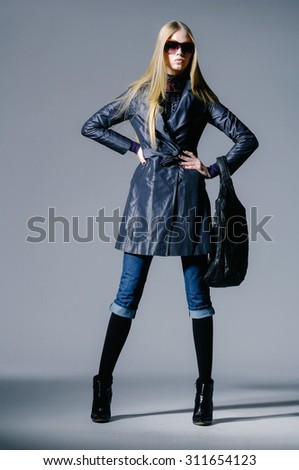 full-length fashion model in autumn/winter clothes holding handbag posing
