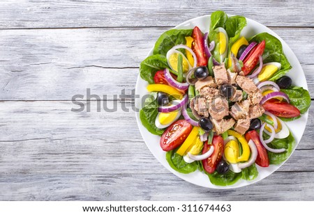 tuna, anchovies, eggs. green been, slices of sweet yellow pepper, red onion, black olives and tomatoes tasty salad on the white plate,  top view Royalty-Free Stock Photo #311674463