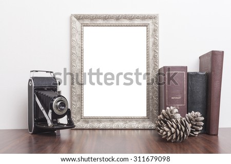 Silver Frame with old books and old camera on wood table