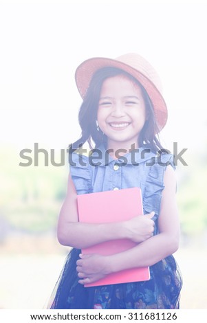 Asian little girl holding a book.Soft focus pastel colour