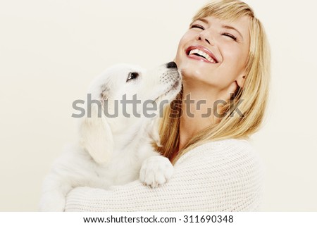 Laughing young woman with pet puppy, studio