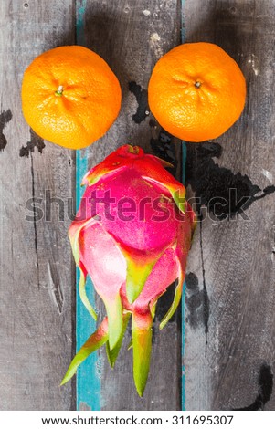 Two orange balls and fruit on a wooden board.