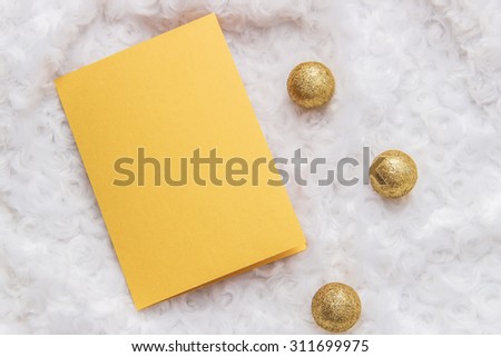 Mockup. Gold card, golden Christmas balls arranged on a white fur.