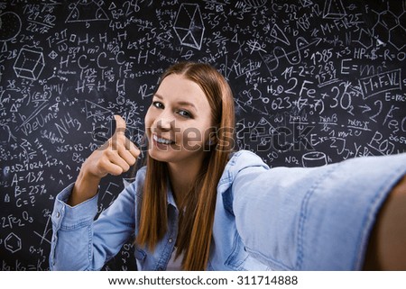 Beautiful student taking selfie in front of big blackboard