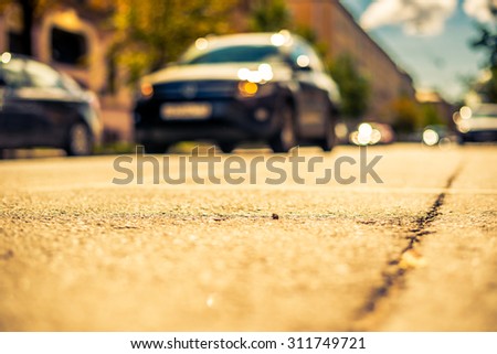 Clear day in the big city, the car goes down the street. View from the level of asphalt, image in the yellow-blue toning