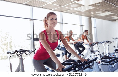 sport, fitness, lifestyle, equipment and people concept - group of women riding on exercise bike in gym