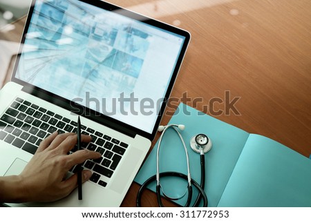 top view of Medicine doctor hand working with modern computer and smart phone on wooden desk as medical concept Royalty-Free Stock Photo #311772953