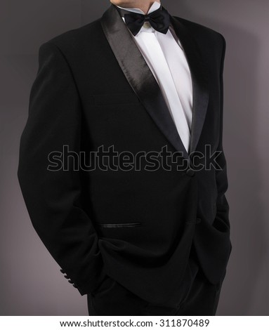 Man in classic tuxedo on abstract dark grey background.photography studio