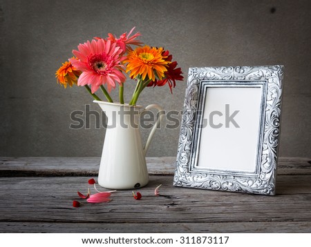 Silver vintage photo frame and flowers on wooden table over grunge background