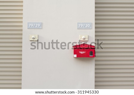 Red mailbox with white lettering on light brown  wall