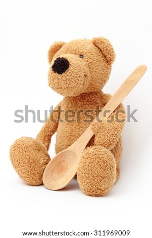 Toy teddy bear with wooden spoon isolated