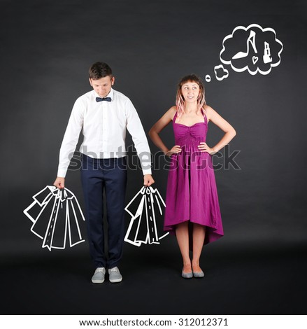 Funny young couple with shopping bags, on black background