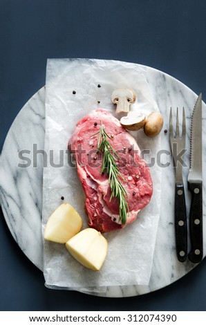 Overhead of raw meat with cutlery, dinner preparation on marble
